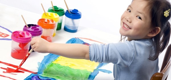Little girl smiling and painting a picture