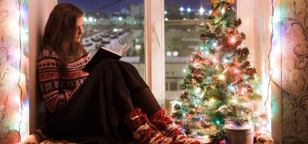 Teen girl reading next to a Christmas tree