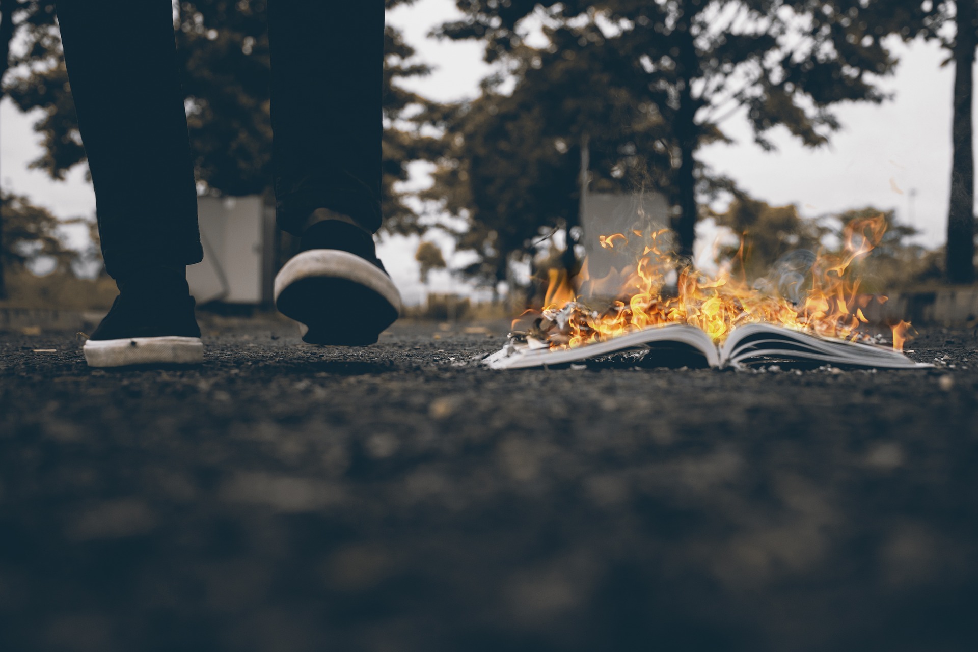 Person shown from the knees down walking next to a burning book.